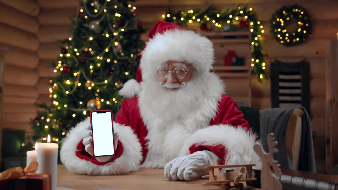 圣诞老人拿着一个空屏幕的智能手机，在镜头前竖起大拇指视频素材