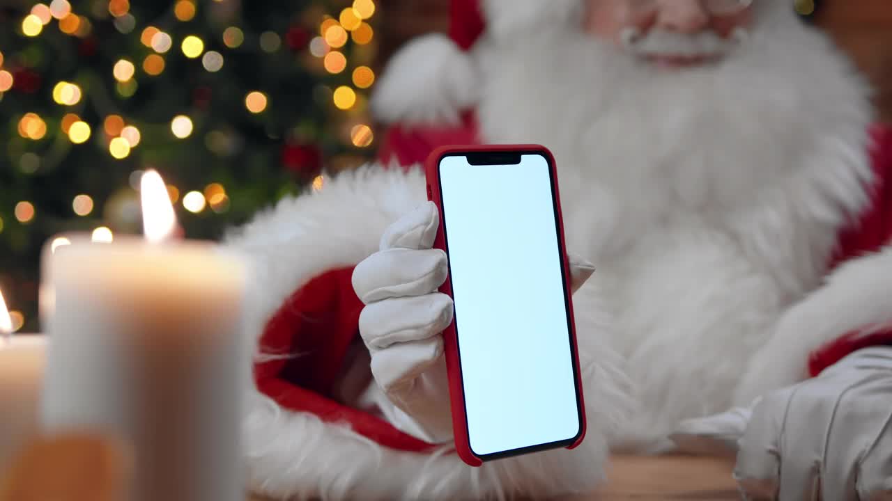 一个圣诞老人的特写镜头显示了一个智能手机的空屏幕，还有竖起的大拇指，视频素材