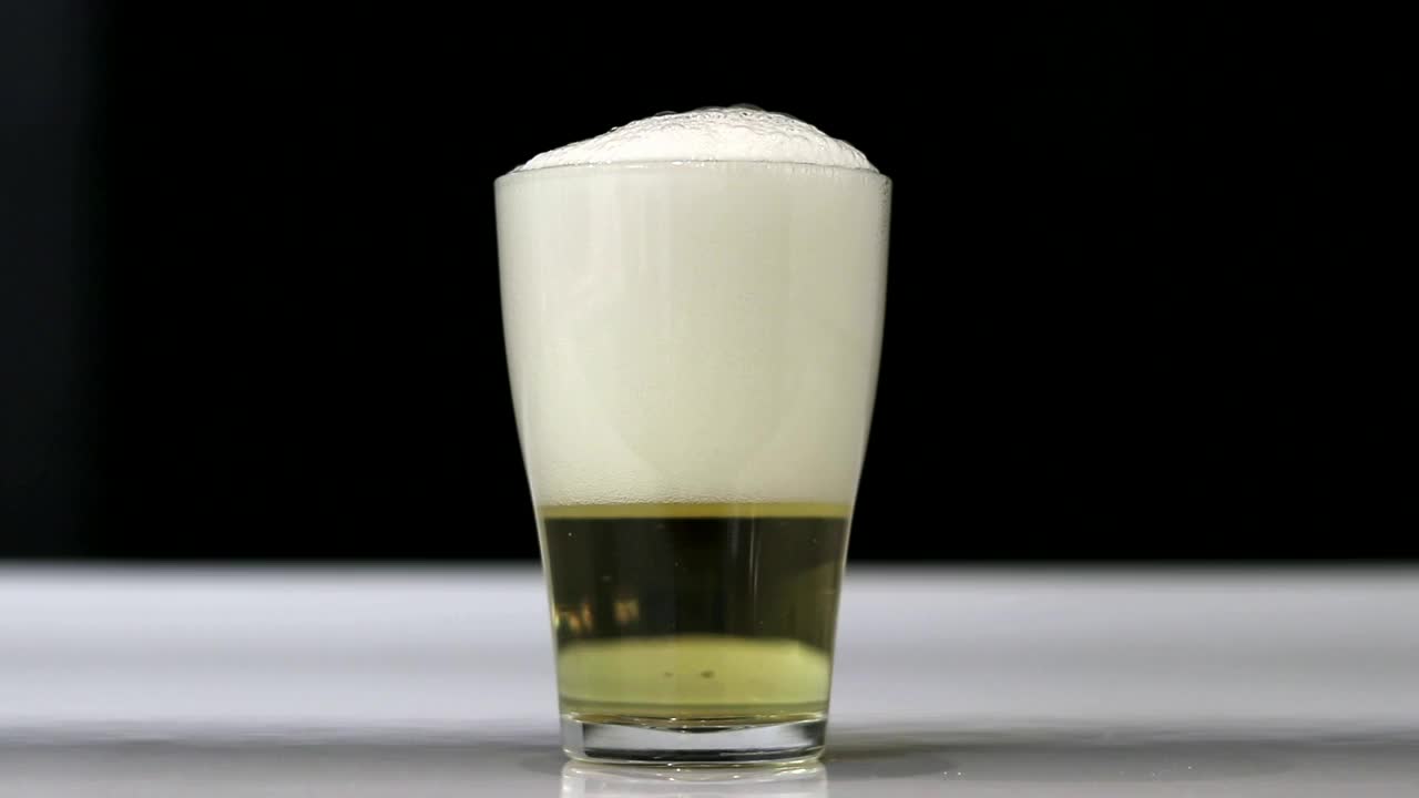 近距离背景倒啤酒与泡沫和泡沫在玻璃，低角度的观点。淡啤酒。视频素材
