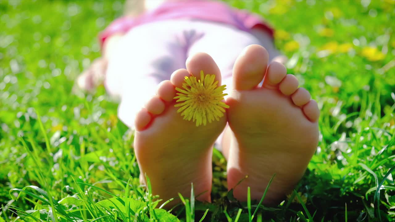 孩子的脚踩在夏天的草地上。有选择性的重点。视频素材