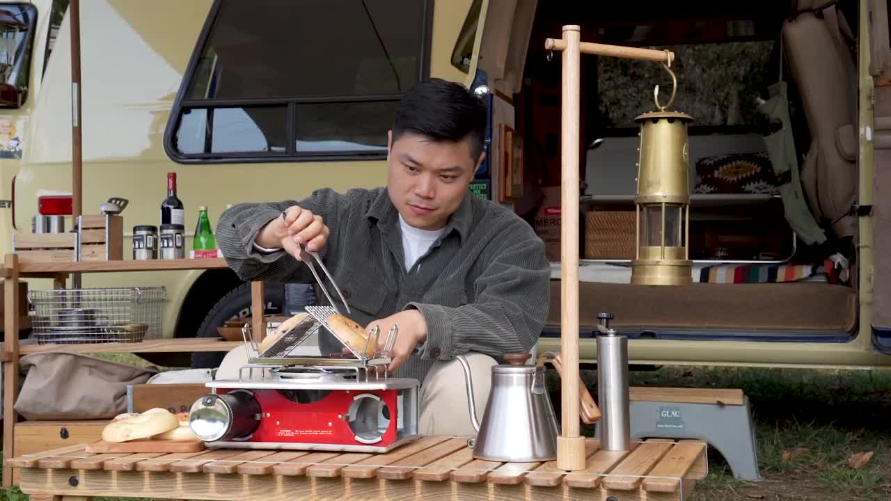 户外露营-年轻人坐在帐篷前的桌子上，用煤气灶烤百吉饼/韩国视频下载