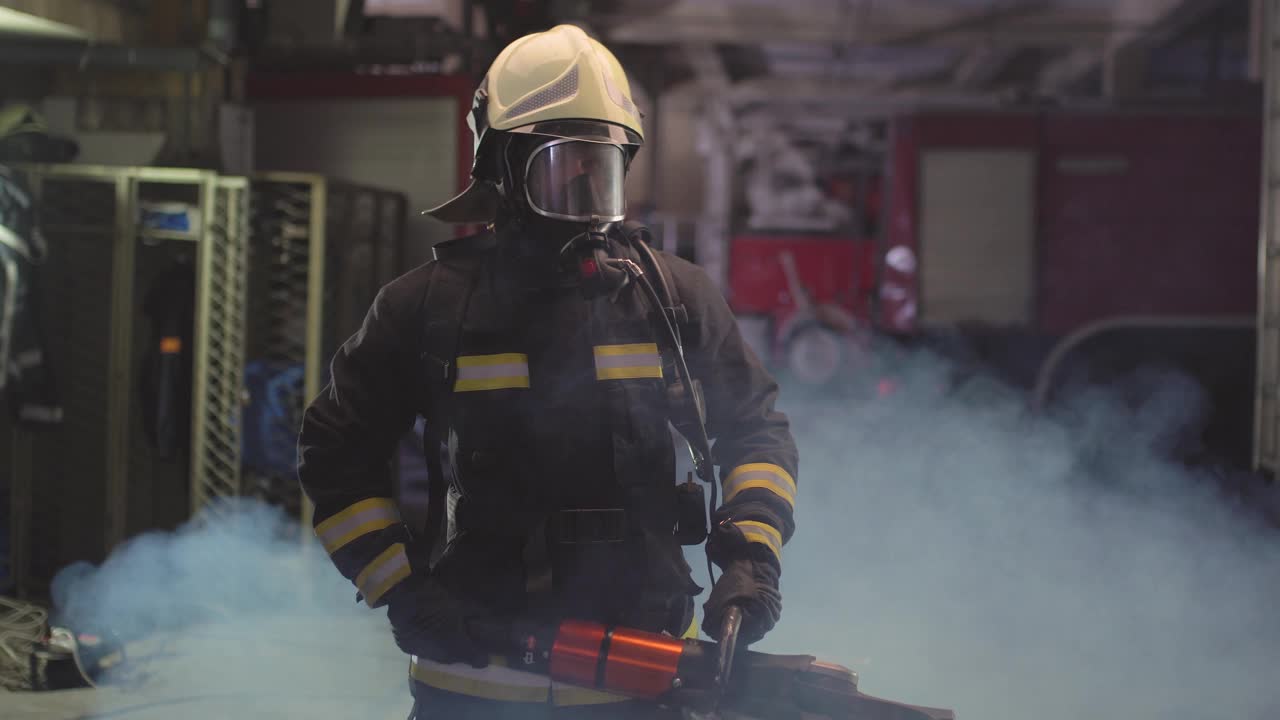 身穿全套装备、氧气面罩、电动液压切割工具的消防员肖像，背景是烟雾和消防车。姓名标签翻译为消防员和模特的姓。视频素材