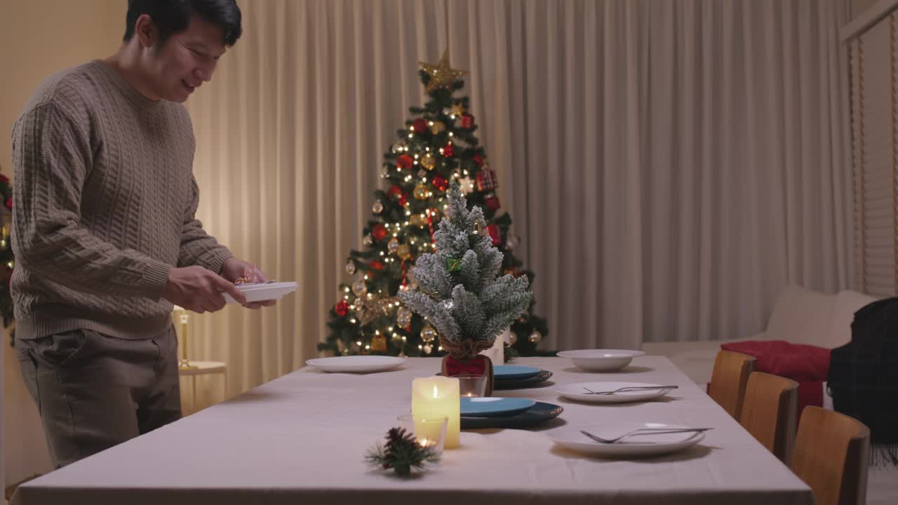 亚洲单身男子今晚准备圣诞夜餐桌布置派对。视频素材