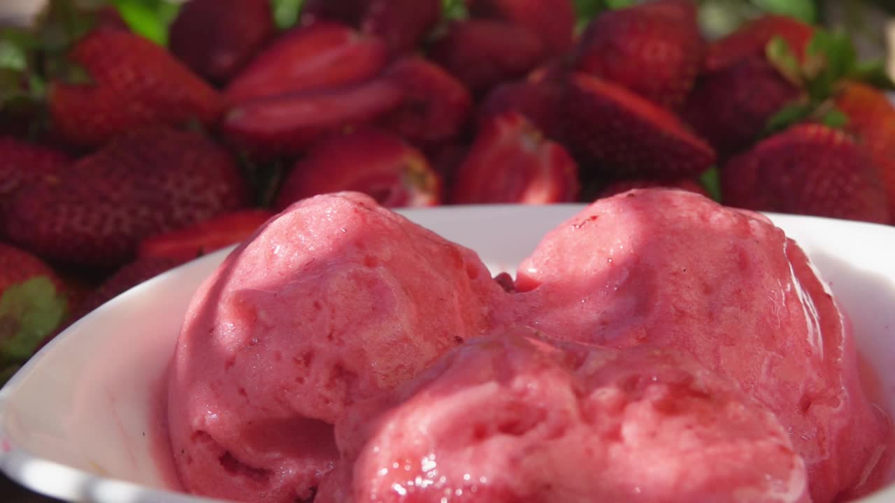 新鲜美味的草莓落在草莓冰淇淋上的特写镜头视频下载
