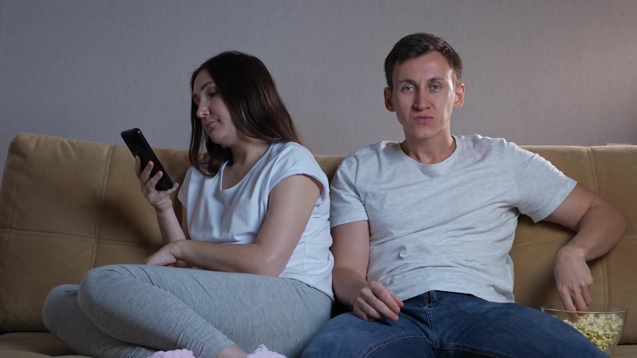 男人高兴地坐在深色头发的女人旁边看电视视频素材