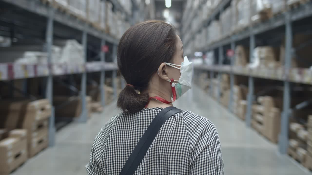 亚洲妇女戴着防护口罩在商店选择产品，慢动作视频素材