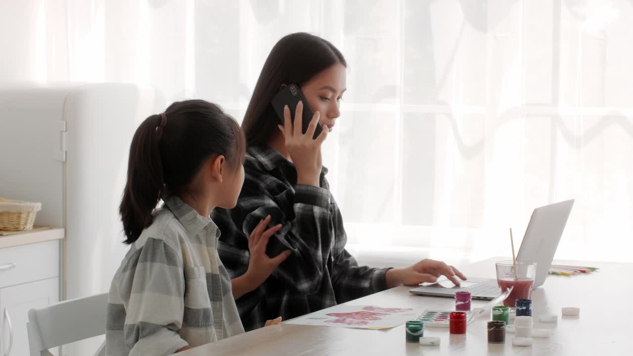 忙碌的亚洲母亲忽视女儿在室内工作讲电话视频下载