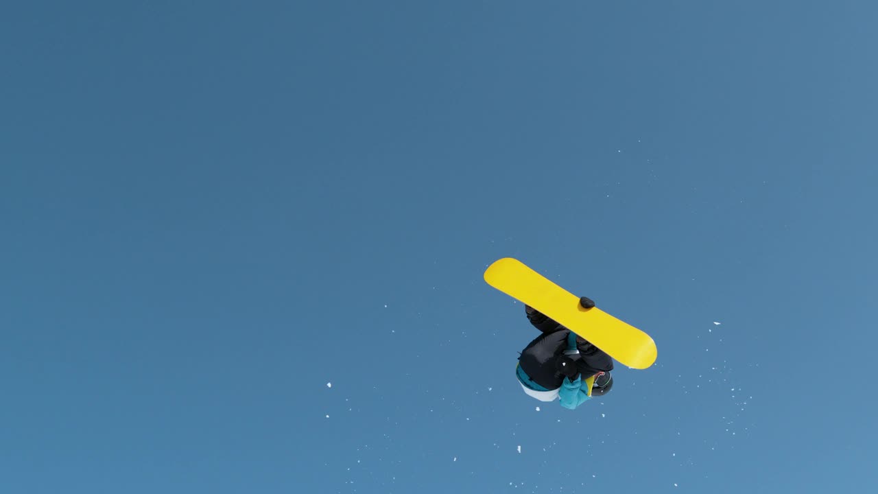 慢动作:单板滑雪运动员跳向空中，表演翻滚旋转技巧。视频素材