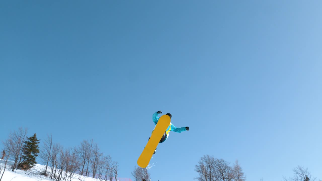 慢动作:运动的男性单板滑雪运动员做了一个可怕的旋转抓取技巧。视频素材