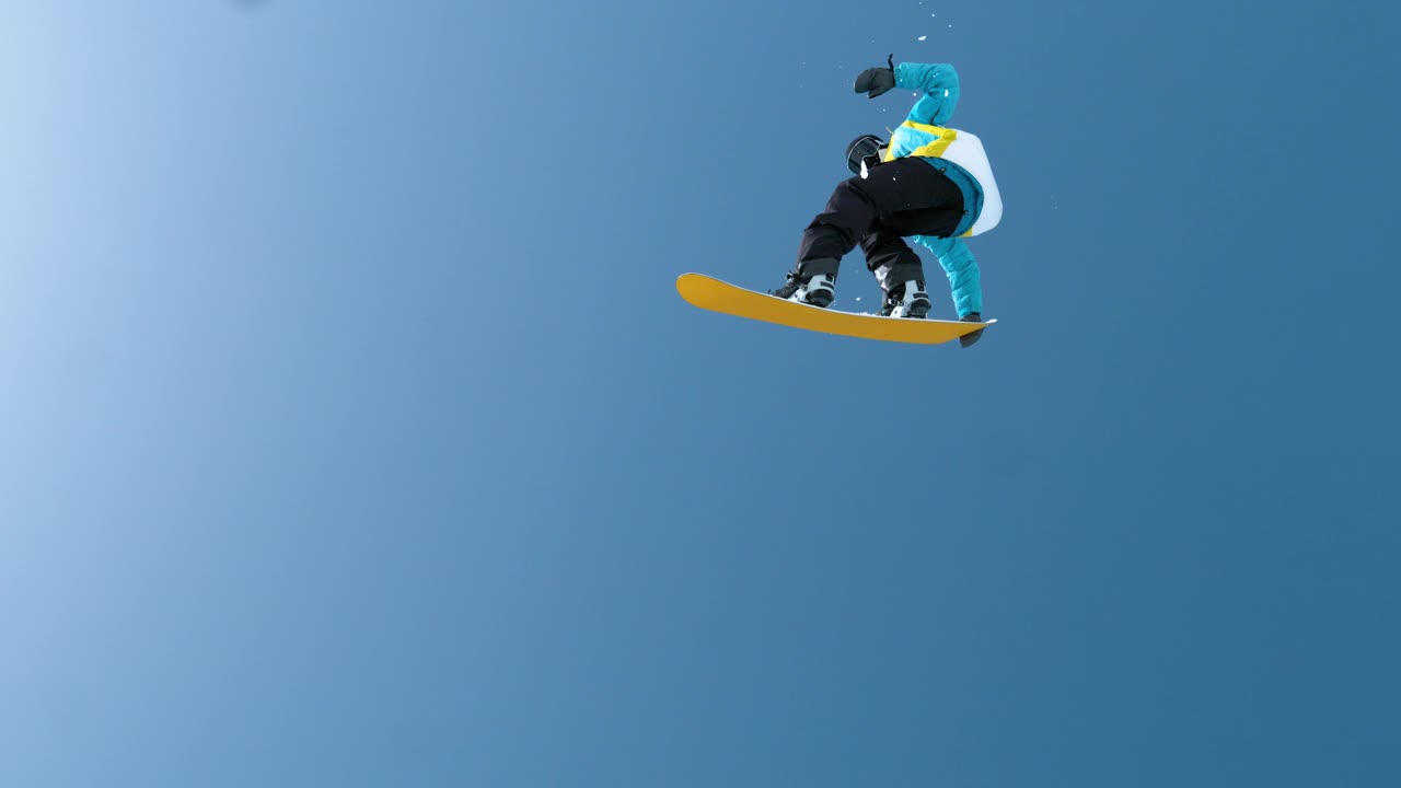 慢镜头:一名男性游客从空中飞过，表演滑雪特技。视频素材