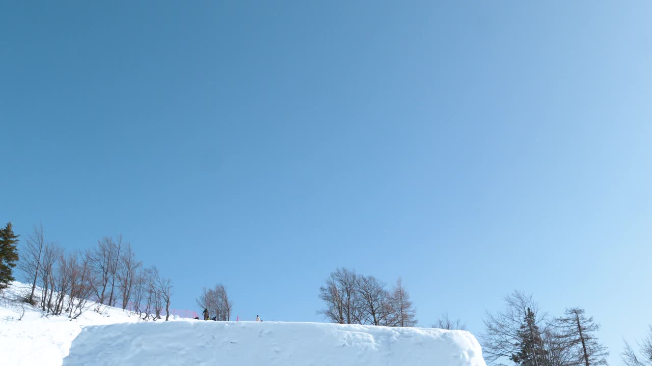 慢动作:滑雪者从踢脚者身上跳下来，做一个旋转的抓球动作。视频素材