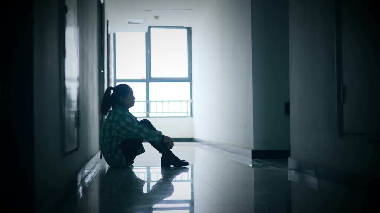 年轻女孩坐在黑暗的走廊里视频素材