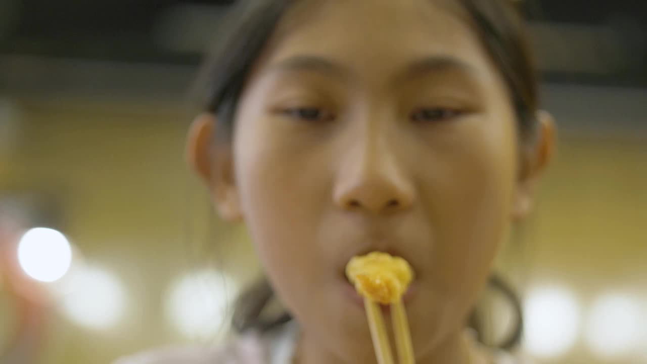 快乐的亚洲女孩和家人一起在日本餐厅享受美食，生活理念。天妇罗从她手中滑落。视频下载