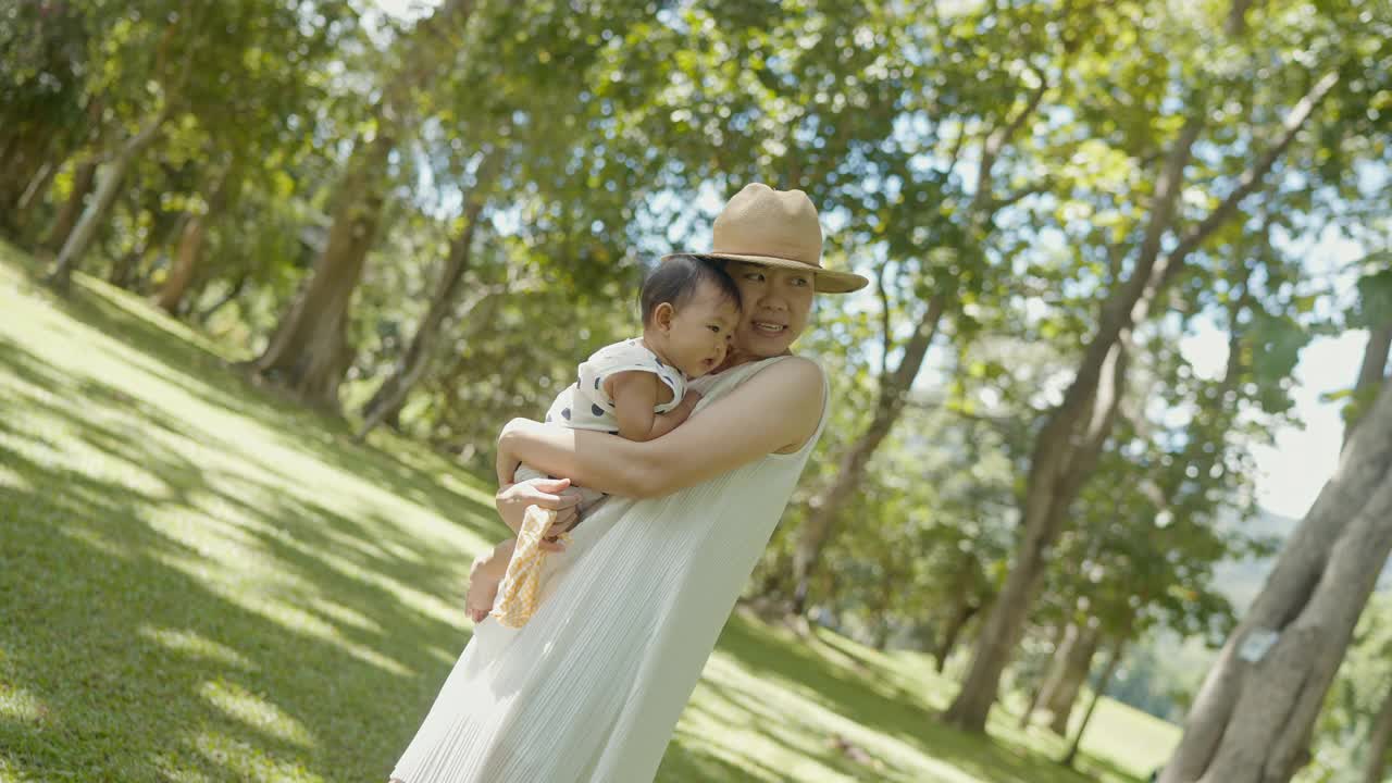 亚洲母亲穿着休闲的衣服，表情和积极的情绪拥抱女儿的休闲和野餐，户外公园和家庭正常的生活方式视频素材