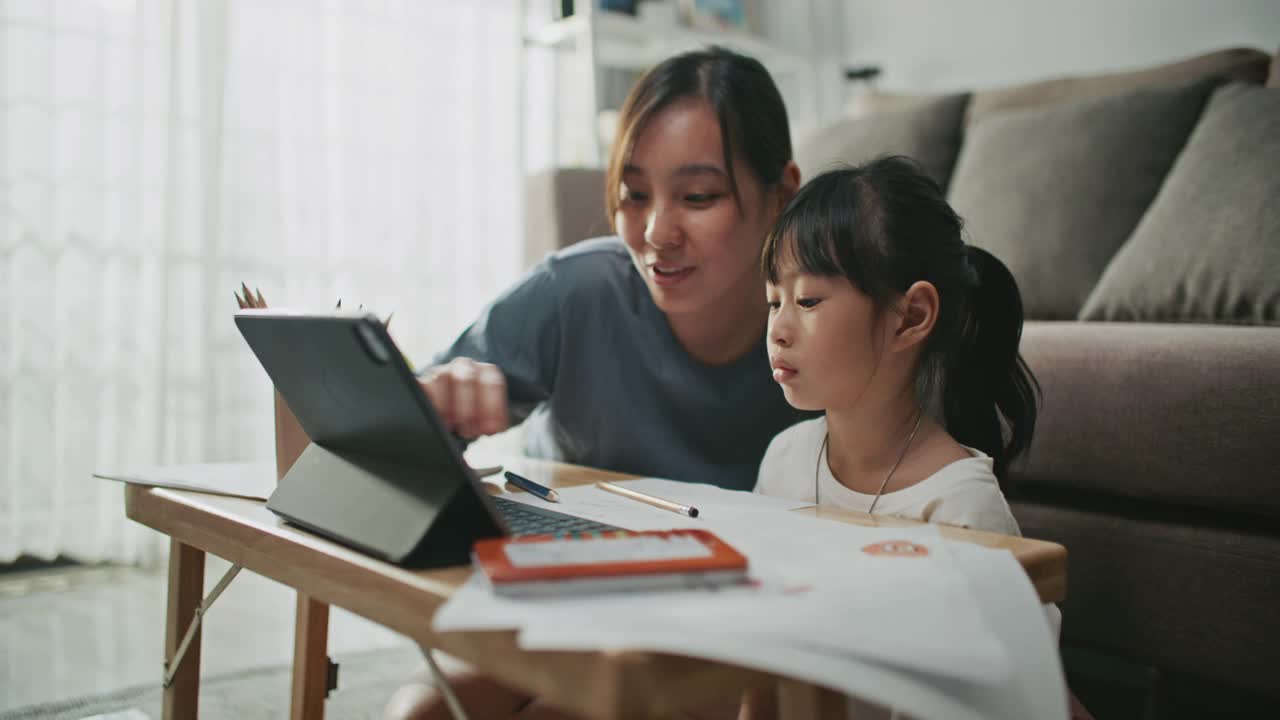 母亲帮助女儿使用笔记本电脑进行家庭教育视频素材