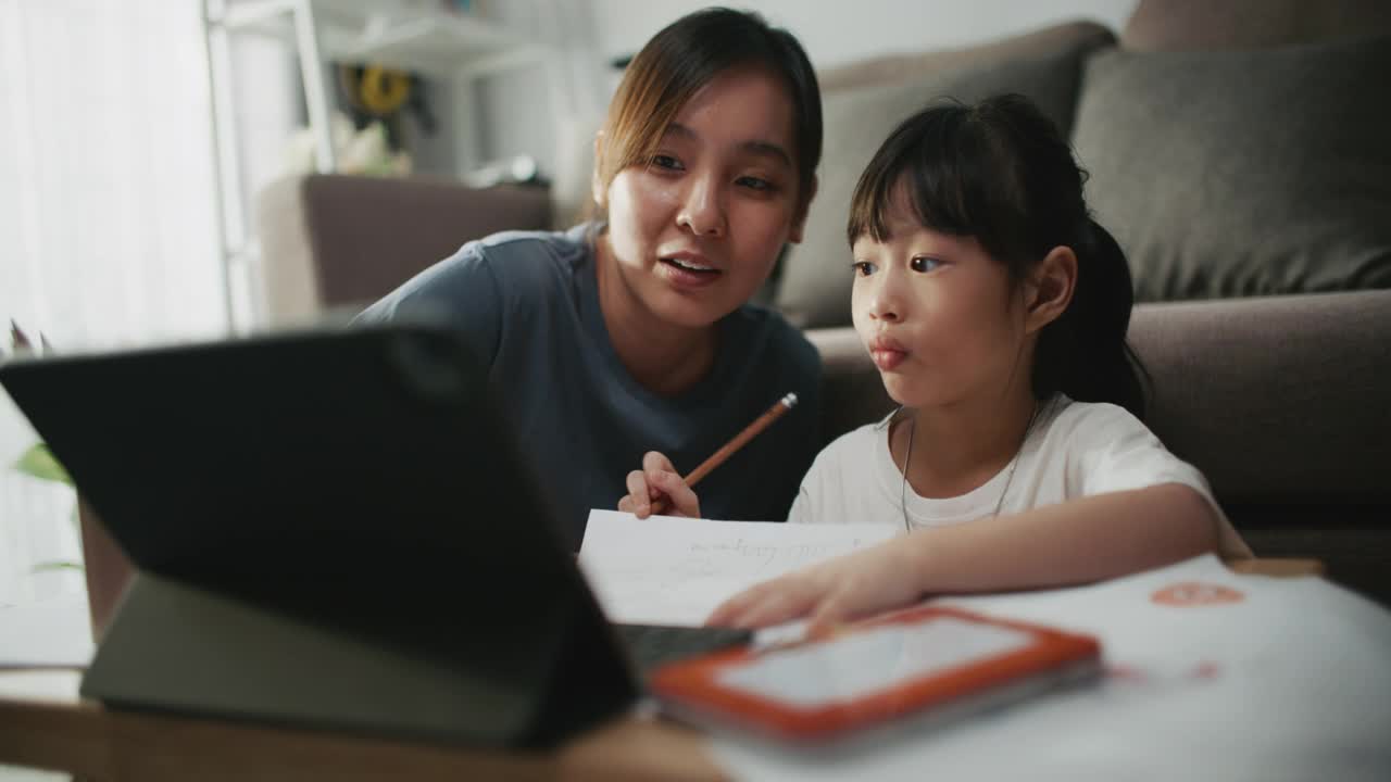 母亲帮助女儿使用笔记本电脑进行家庭教育视频素材