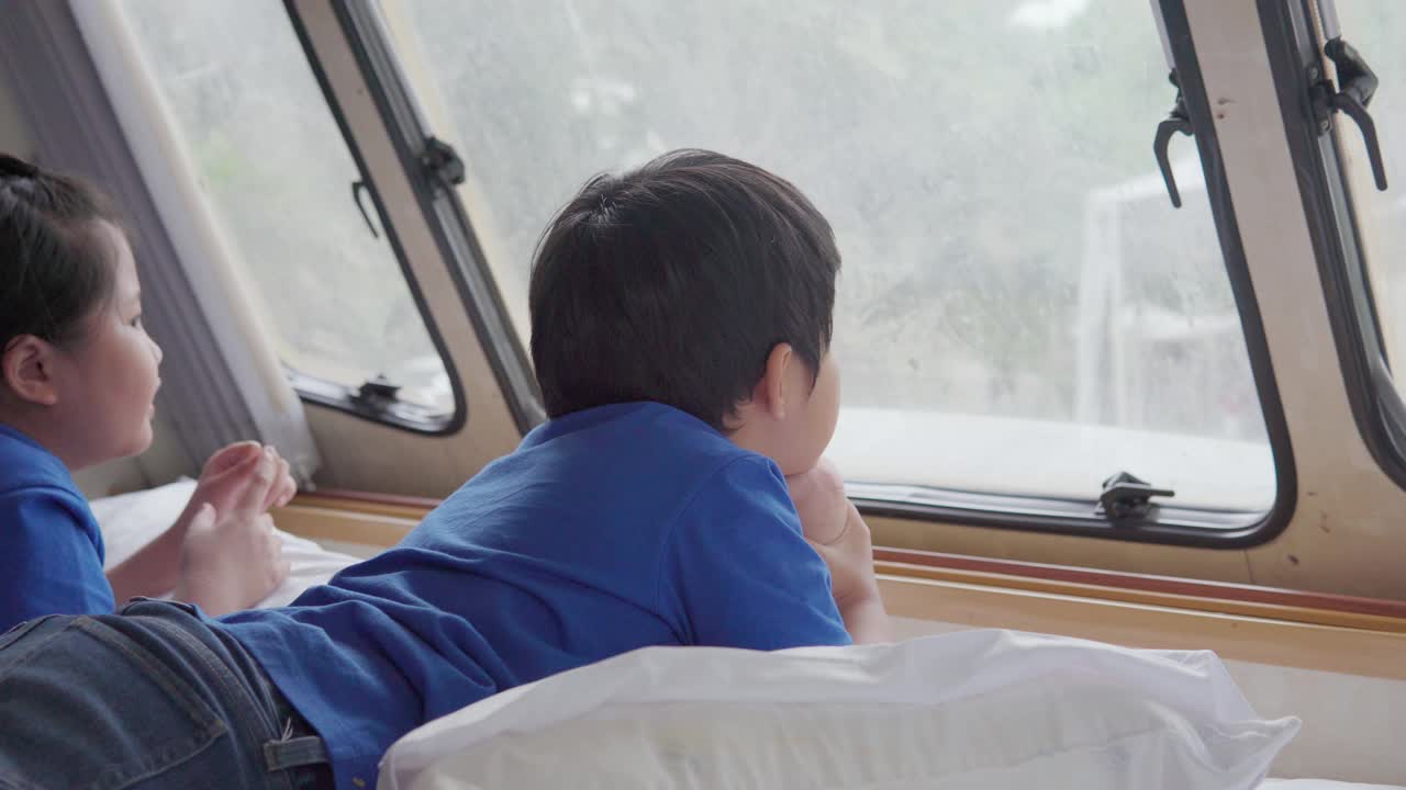 亚洲兄弟和姐妹感觉放松在一辆露营车与窗外的景色在假日早上视频素材