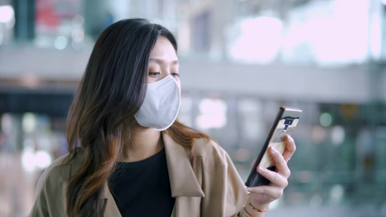 旅客佩戴外科口罩，用智能手机查看登机牌。视频下载