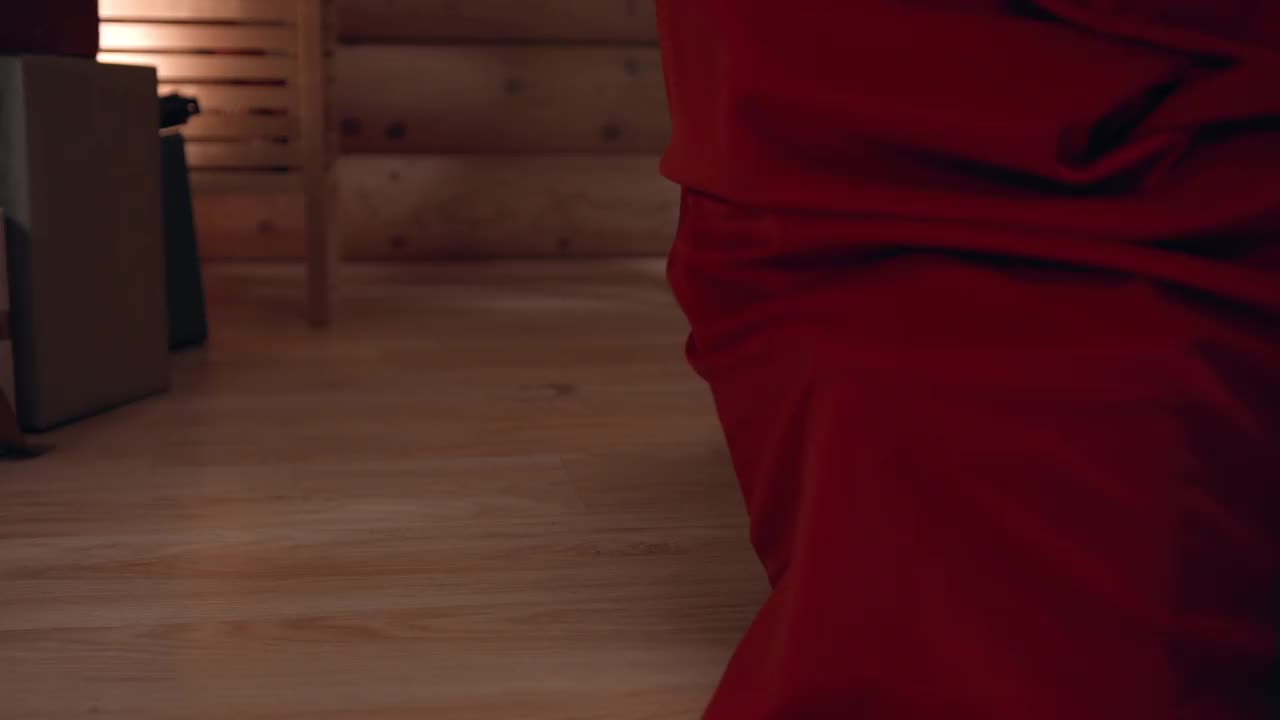 圣诞老人的脚穿着靴子，走在堆满礼物的房子的木地板上的特写视频下载