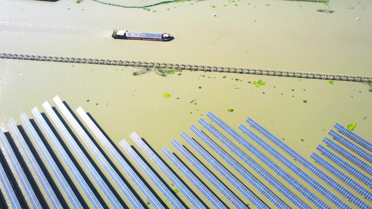 在阳光明媚的日子里，一艘船在湖面上航行，经过漂浮的太阳能电池板农场视频下载