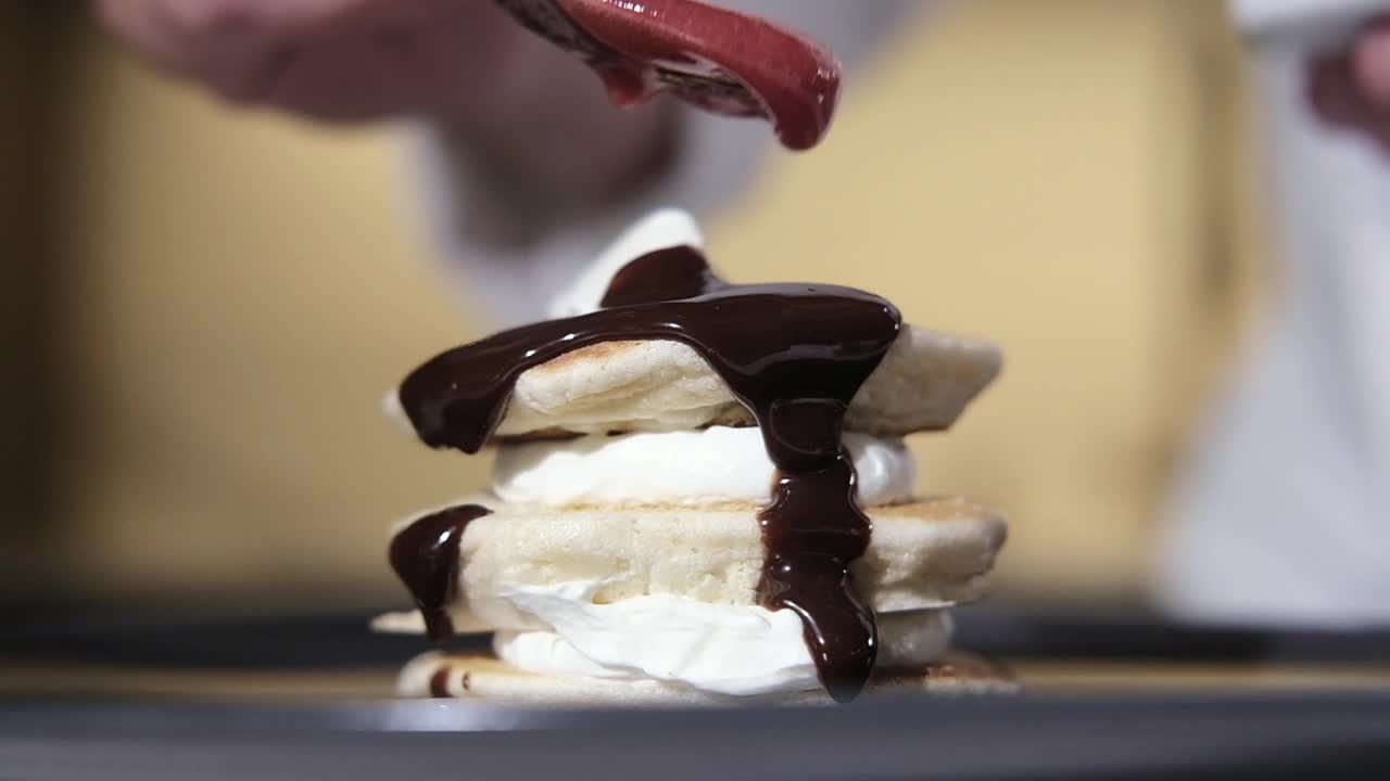 厨师用勺子将热巧克力和浆果糖浆倒在甜点上视频下载