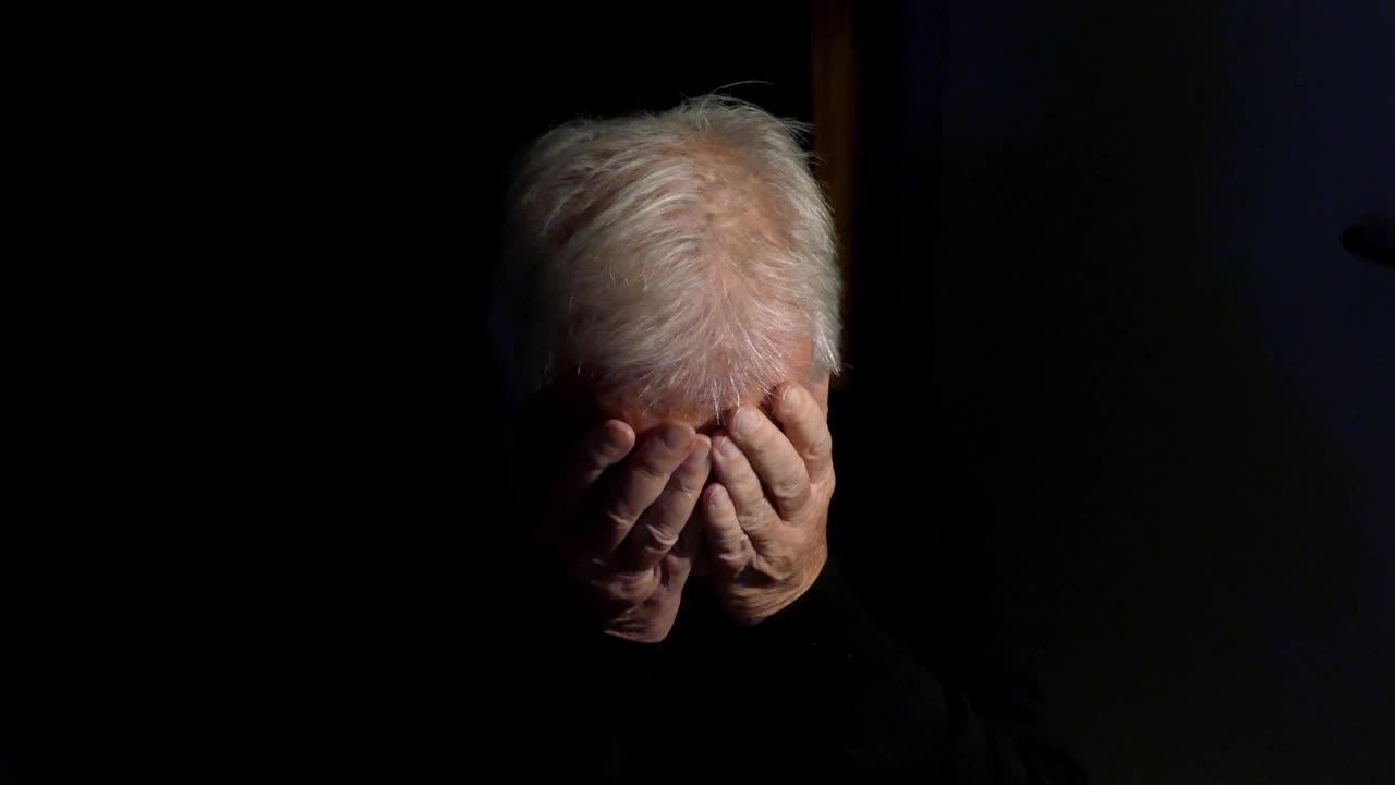 一个抑郁的老人独自在黑暗中视频素材