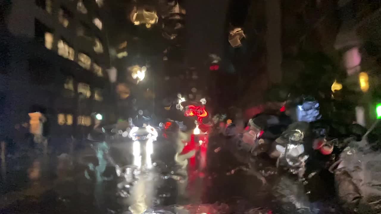 在城市的夜晚，雨落在挡风玻璃上视频下载