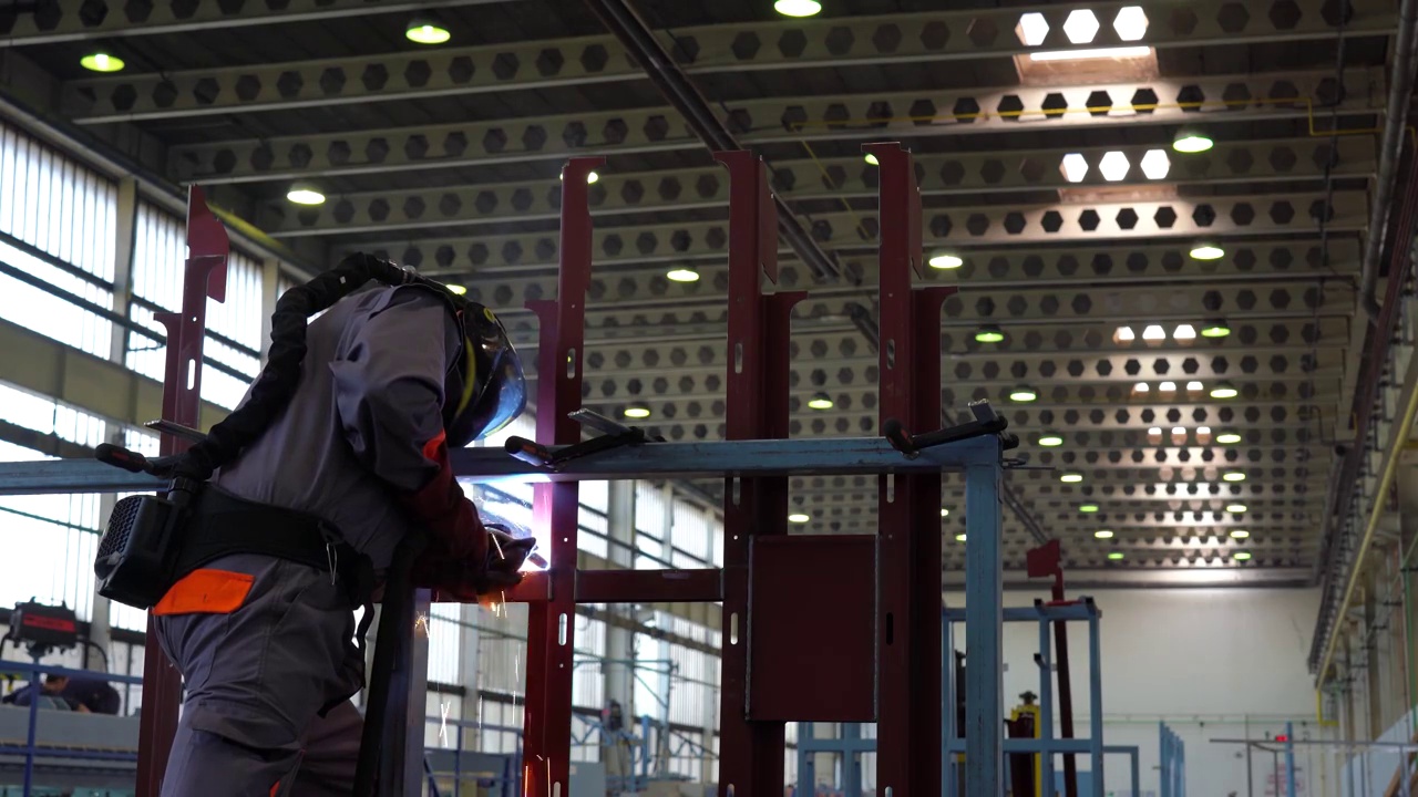 工人在焊接头盔和防护工作服在工厂焊接视频素材