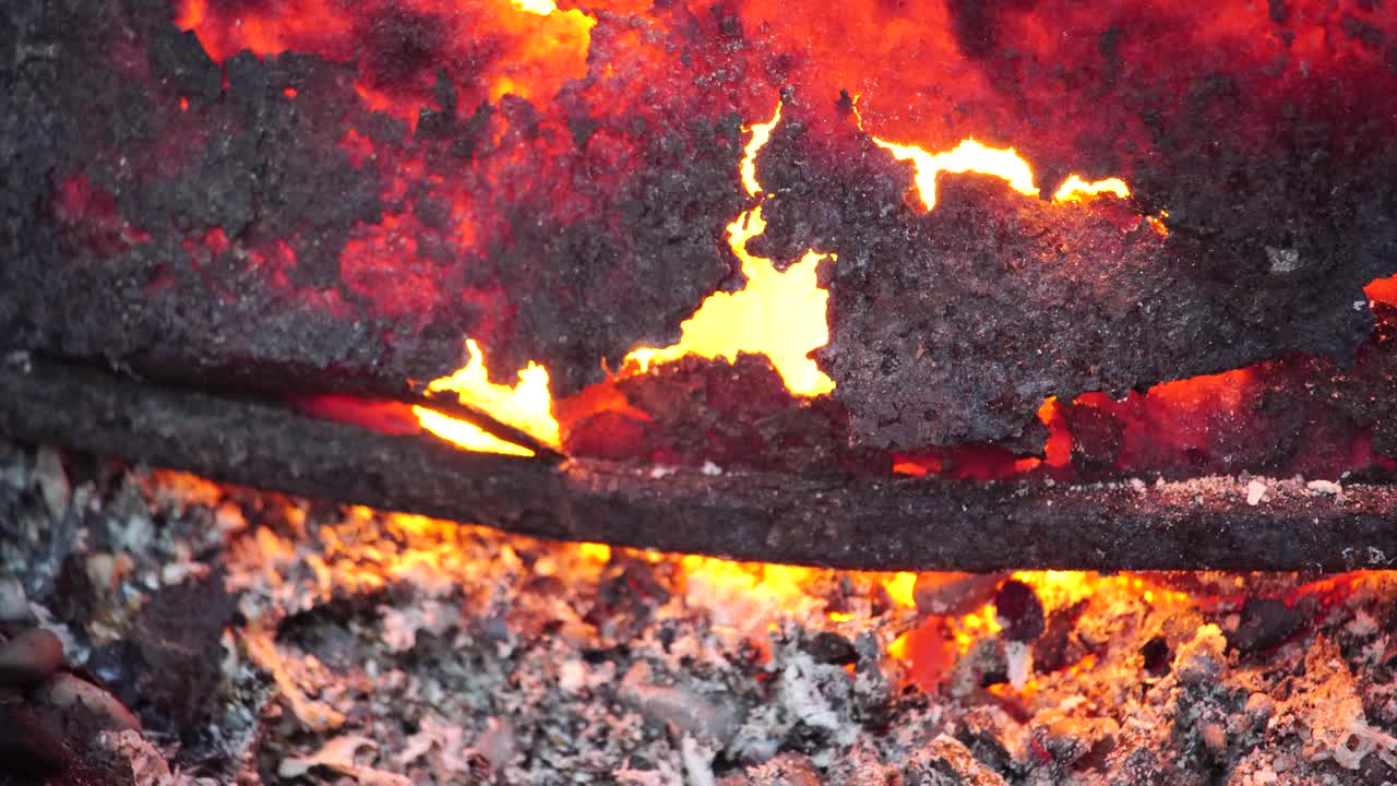 近距离拍摄一个大的明亮的红色火在烧烤架，火盆。明亮的篝火闪烁着明亮的灯光，灰烬、烟雾和火花在黑暗中燃烧视频下载