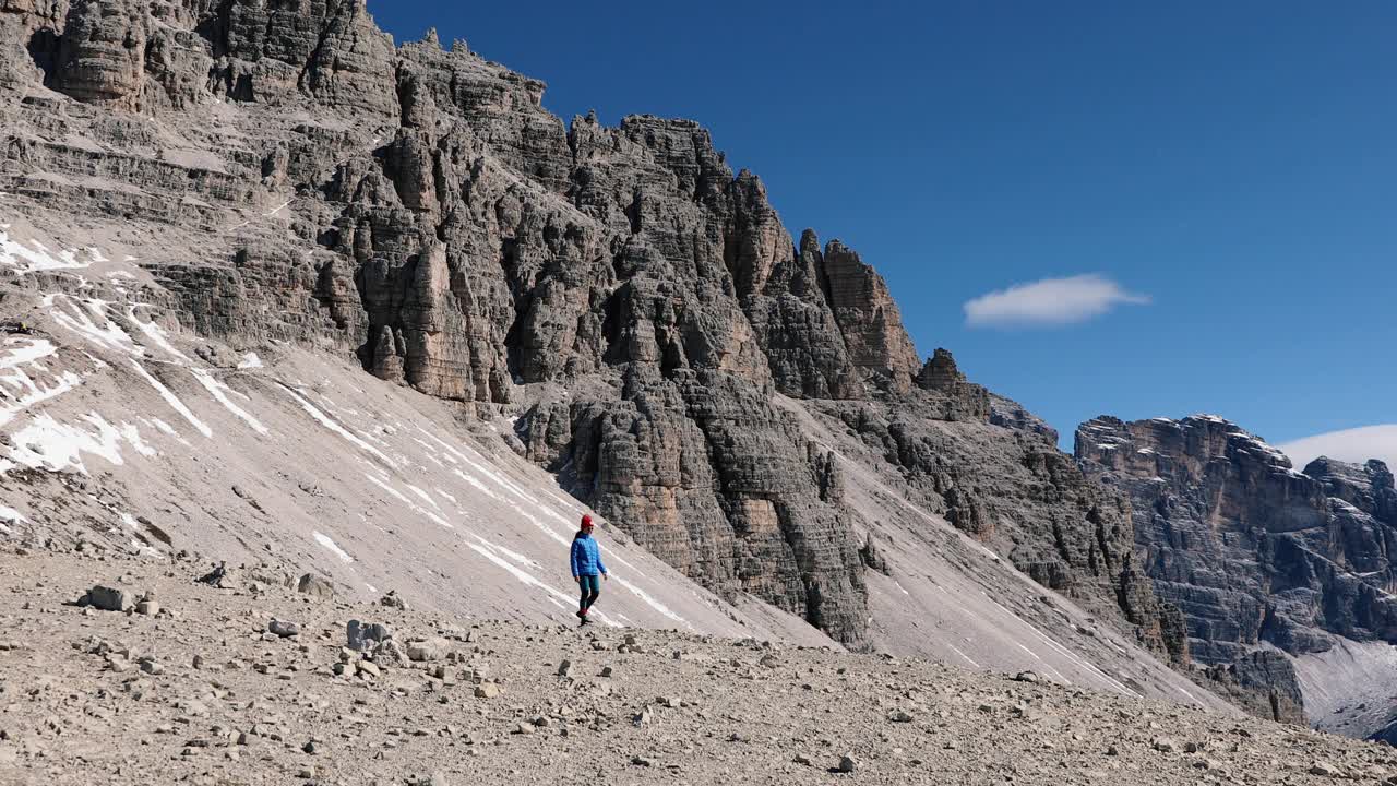 一名女性徒步旅行者沿着小路行走，可以看到阳光普照的阿尔卑斯山山脉视频素材