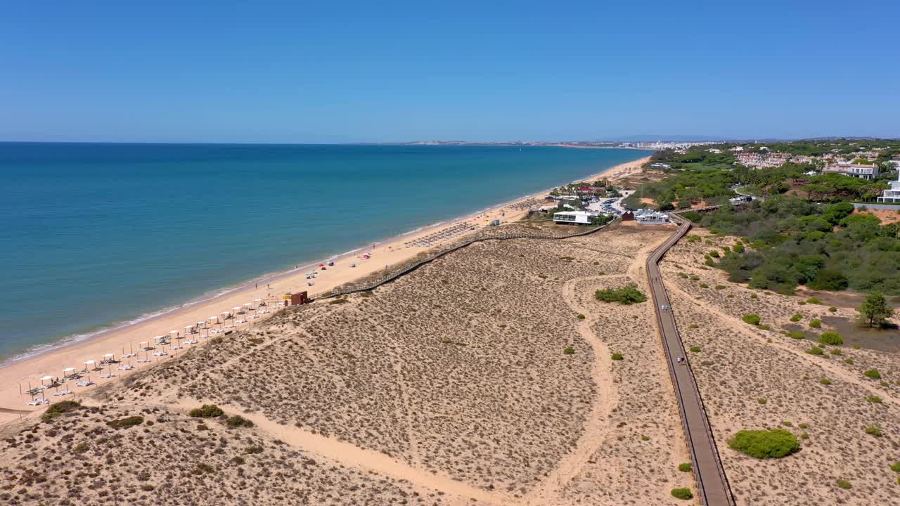 无人机拍摄的沙滩沙丘和通往大海的木路。葡萄牙,阿尔加维。视频素材