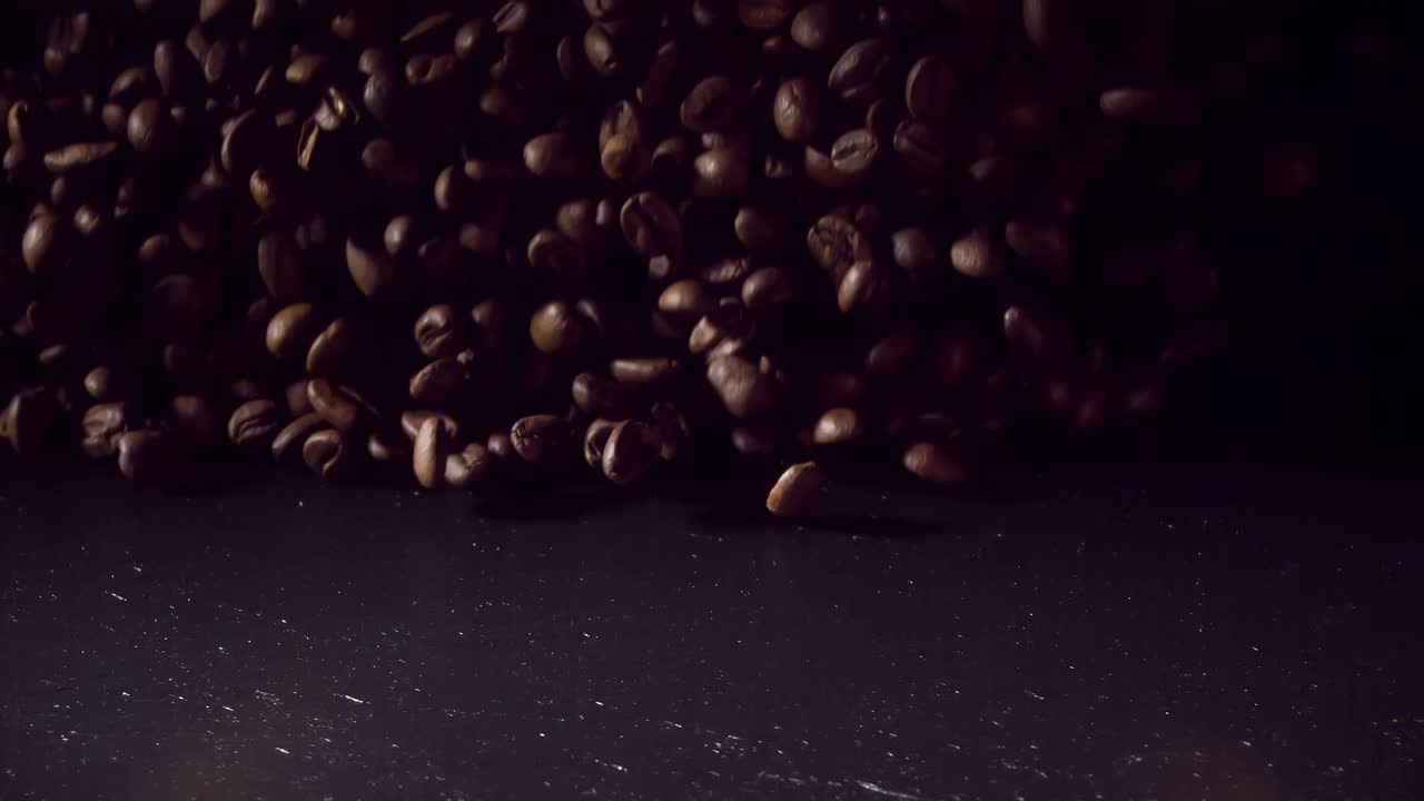 以1000帧/秒的速度，咖啡豆落在黑暗的石头上。超级慢动作视频素材