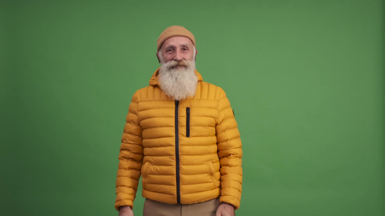 一个英俊的老头微笑着展示着文案空间。绿色背景。一个人视频素材