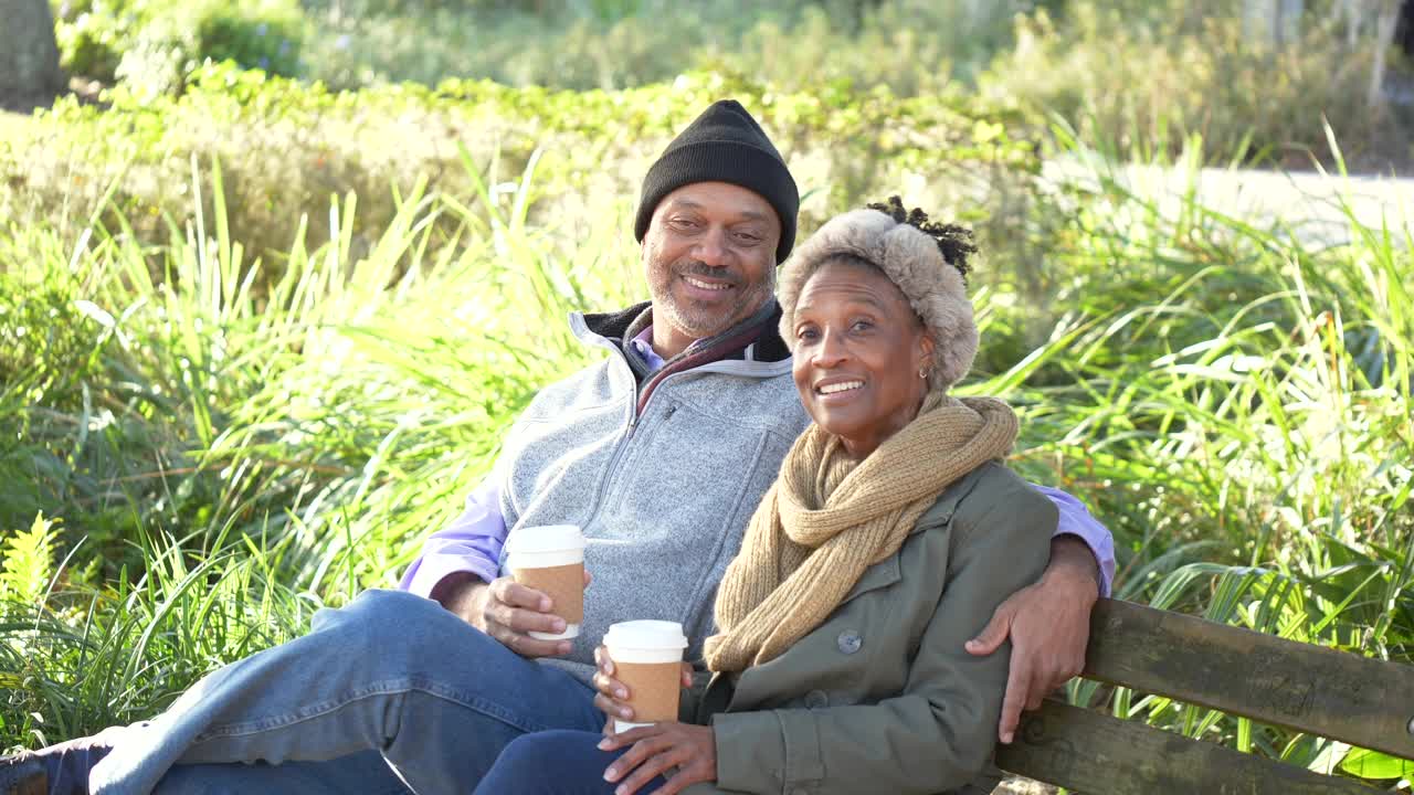 非裔美国夫妇在公园长椅上休息，喝咖啡视频素材