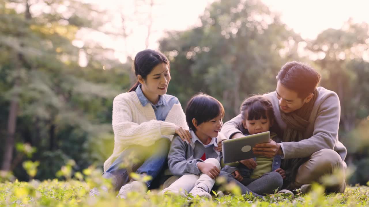 年轻的亚洲家庭在公园草地上放松视频素材