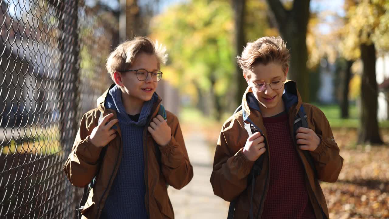 两个男孩在秋天步行上学视频下载
