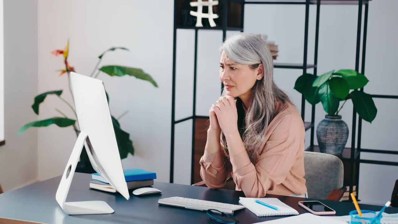 高级商业女性被压力、焦虑搞糊涂了，在办公室的电脑前超负荷工作视频素材