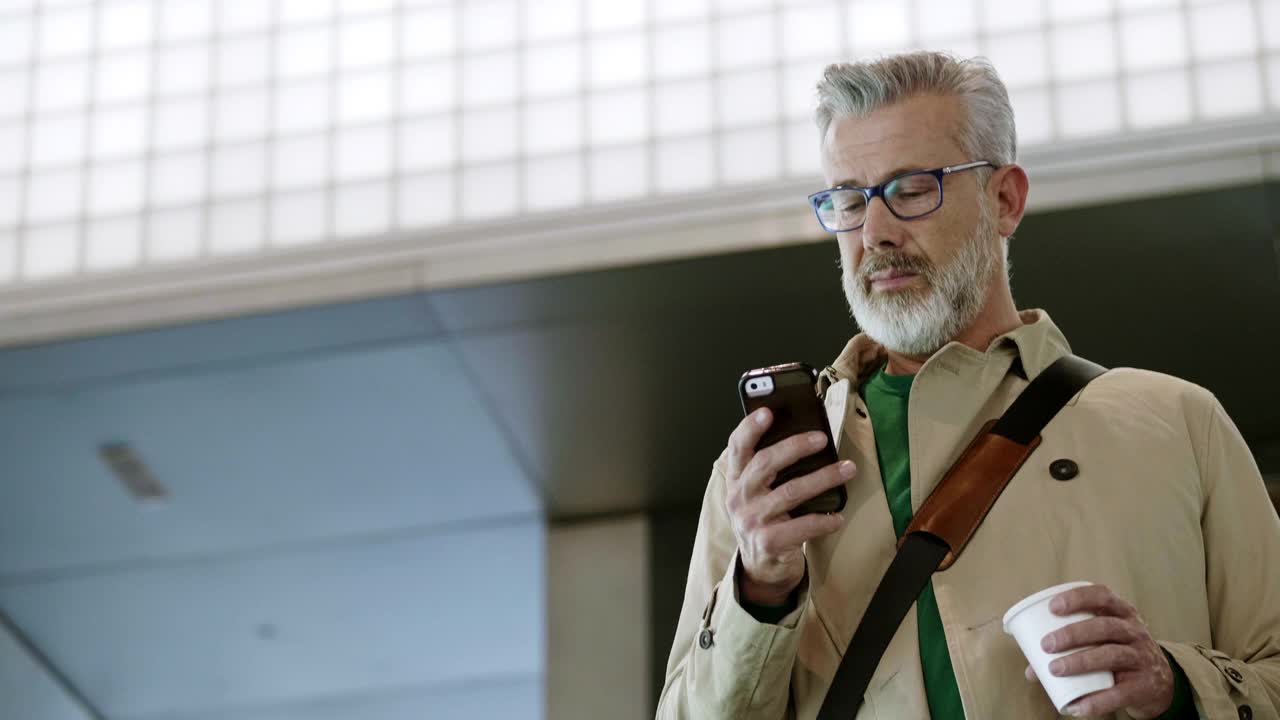 成熟的商人在机场使用智能手机视频下载