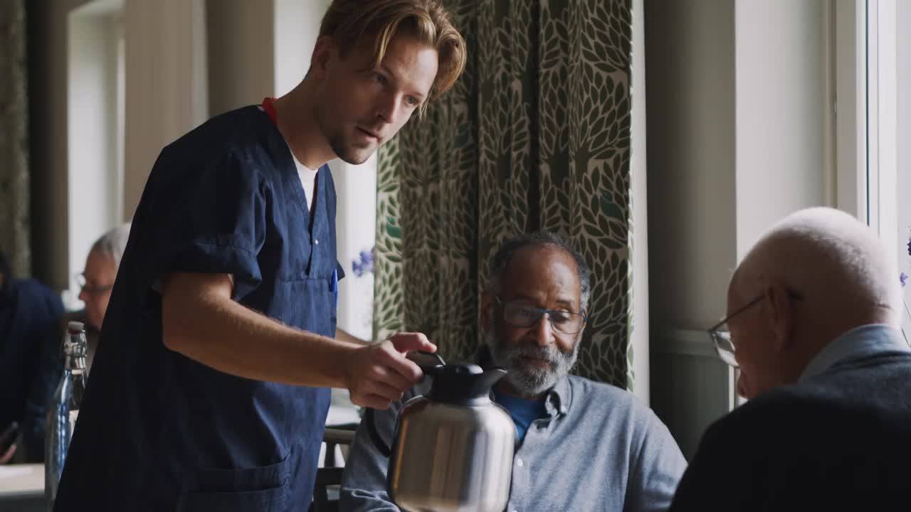 养老院的男保健员给老人倒咖啡的慢动作视频下载
