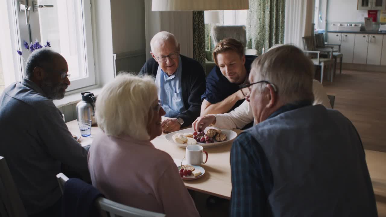 敬老院的老人一边吃早餐，一边和男看护者聊天视频素材