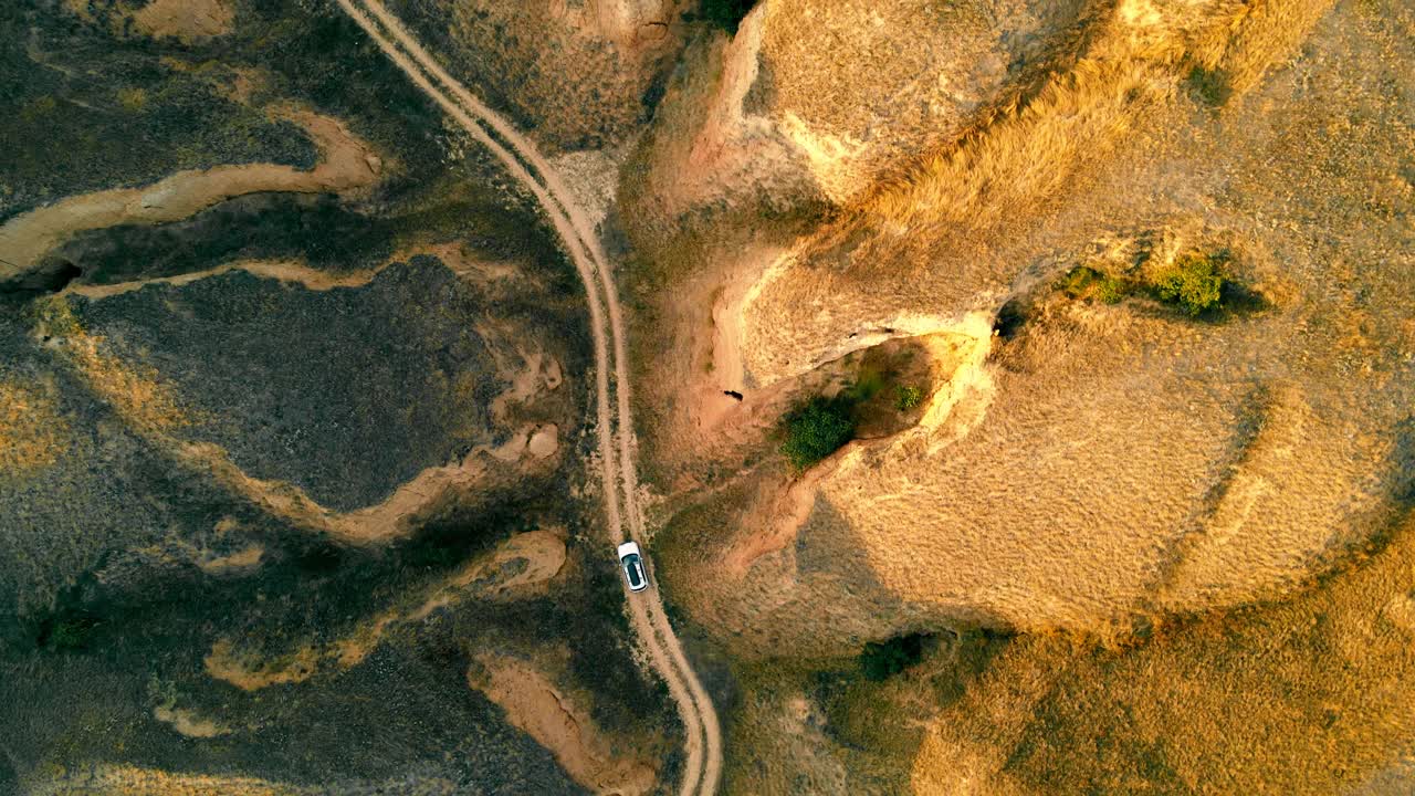 鸟瞰图上的汽车在山上的土路移动。汽车在沙丘之间的移动。峡谷旅行视频素材