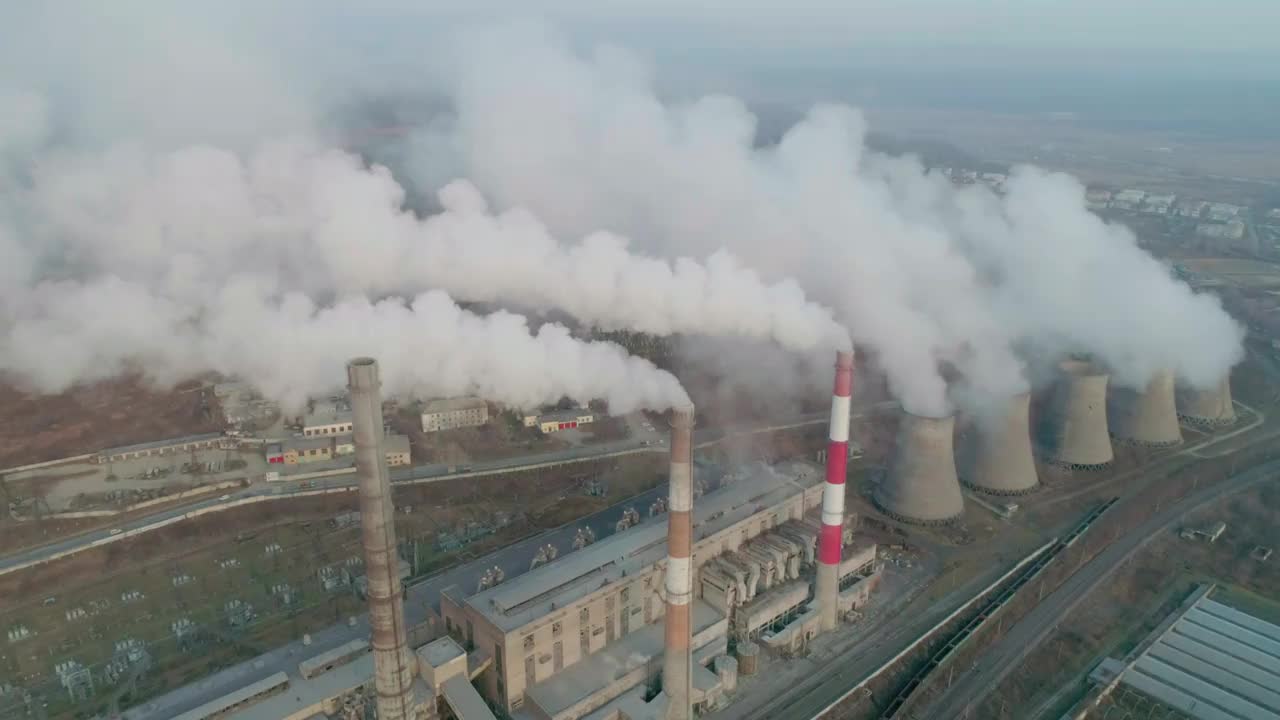 鸟瞰图，工业园区的管道倾泻着浓浓的白烟。浓烟滚滚。火力发电厂管道、空气污染。视频素材