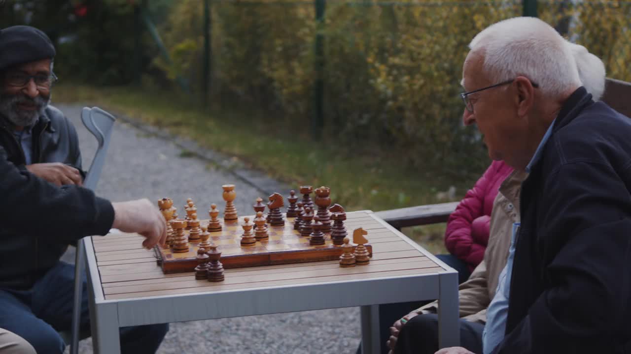 老年男子与男女朋友在公园下棋的慢动作视频素材