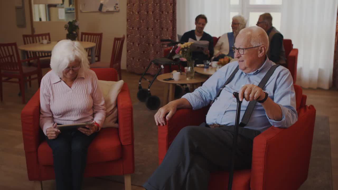 在养老院，女护士帮老人穿毛衣的手持式照片视频下载