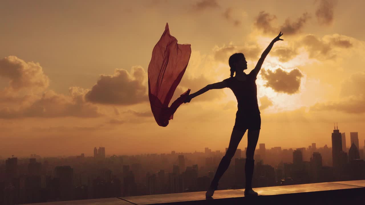 年轻快乐的女子在美丽的夕阳下舞动，现代都市的背景视频下载