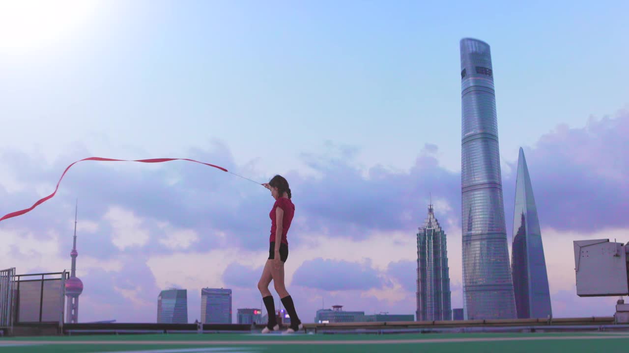 中国上海，一名年轻的女芭蕾舞者在屋顶上用红丝带跳舞视频素材