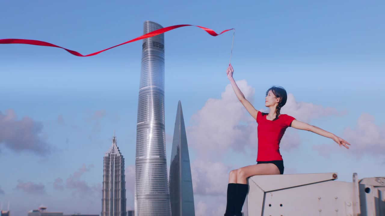 中国上海，一名年轻的女芭蕾舞者在屋顶上用红丝带跳舞视频素材