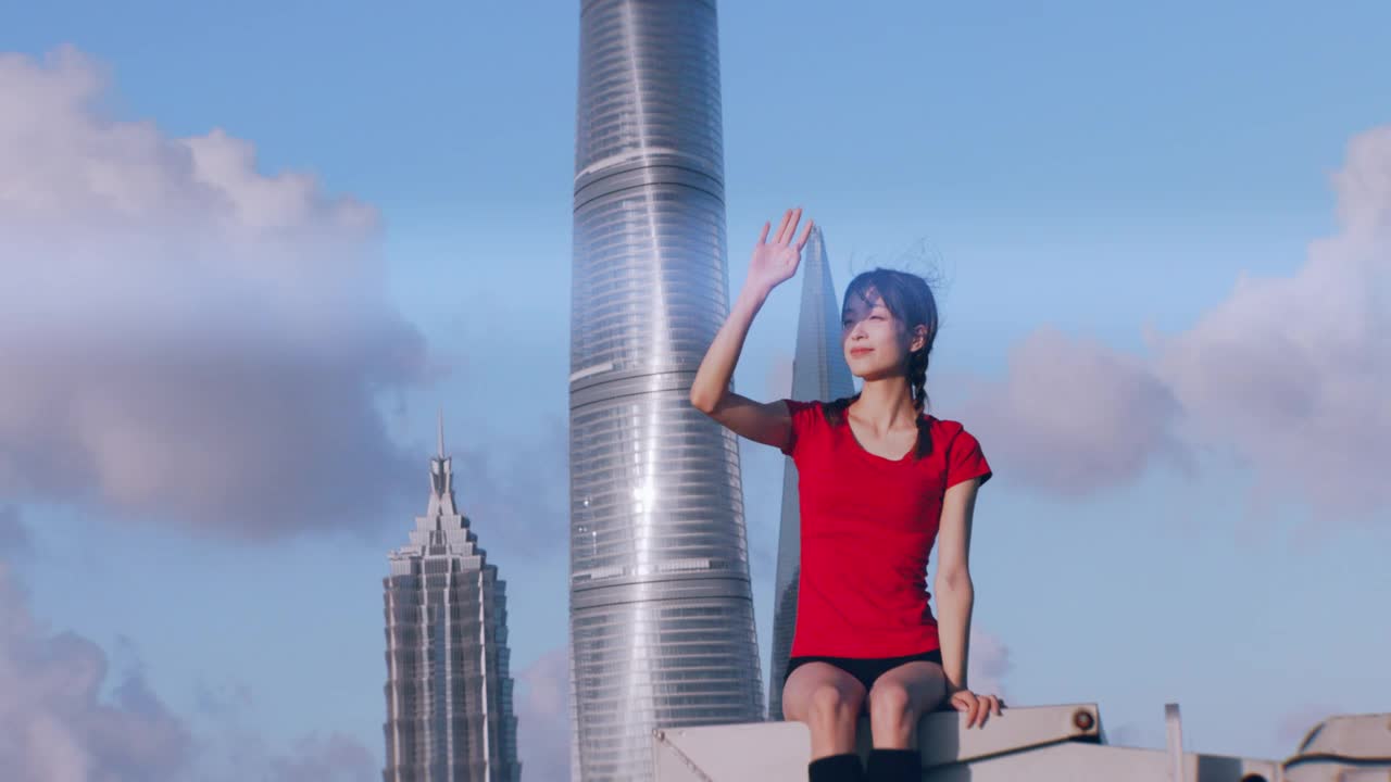 一位年轻的芭蕾舞女演员在楼顶看夕阳，背景是上海的地标建筑视频素材