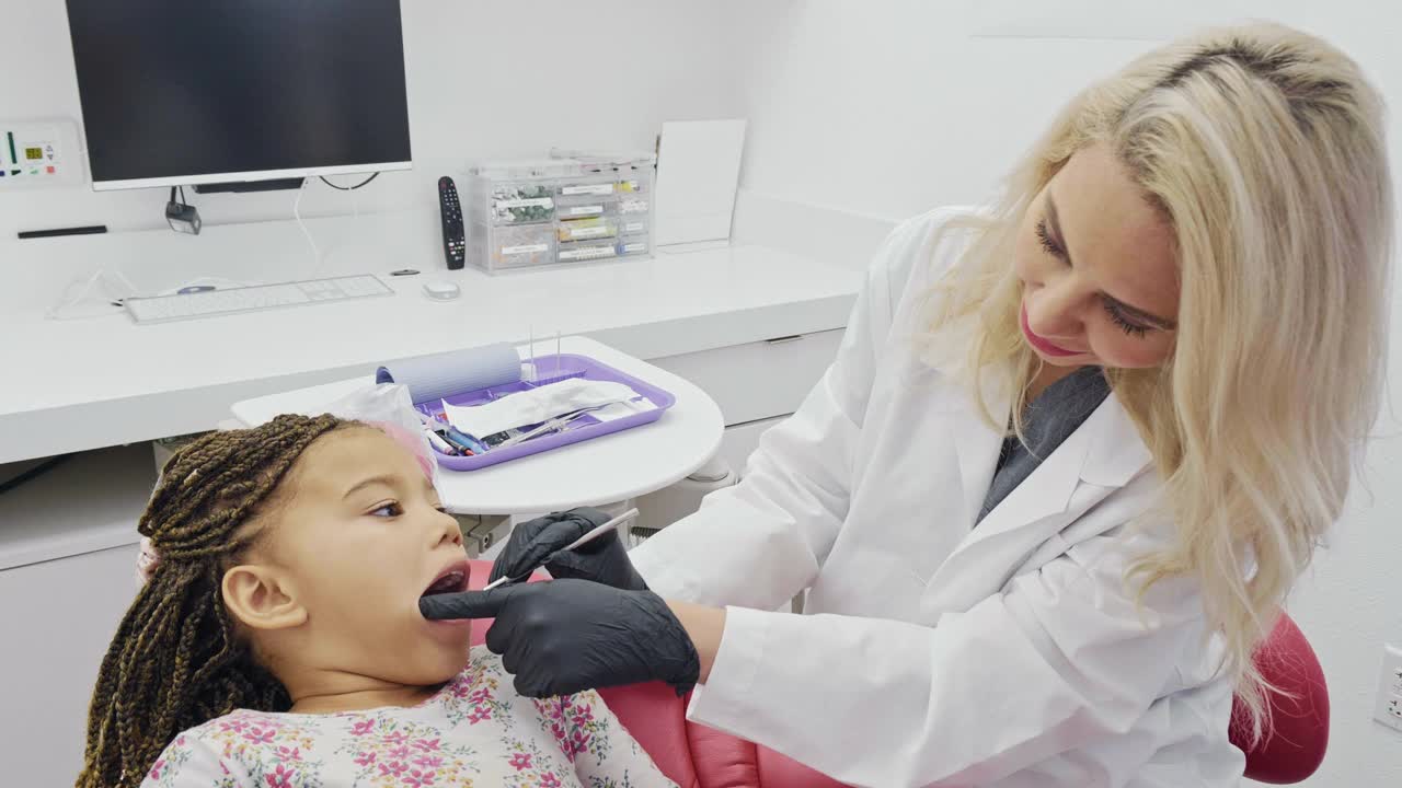 女牙医检查小学女孩的牙齿视频下载