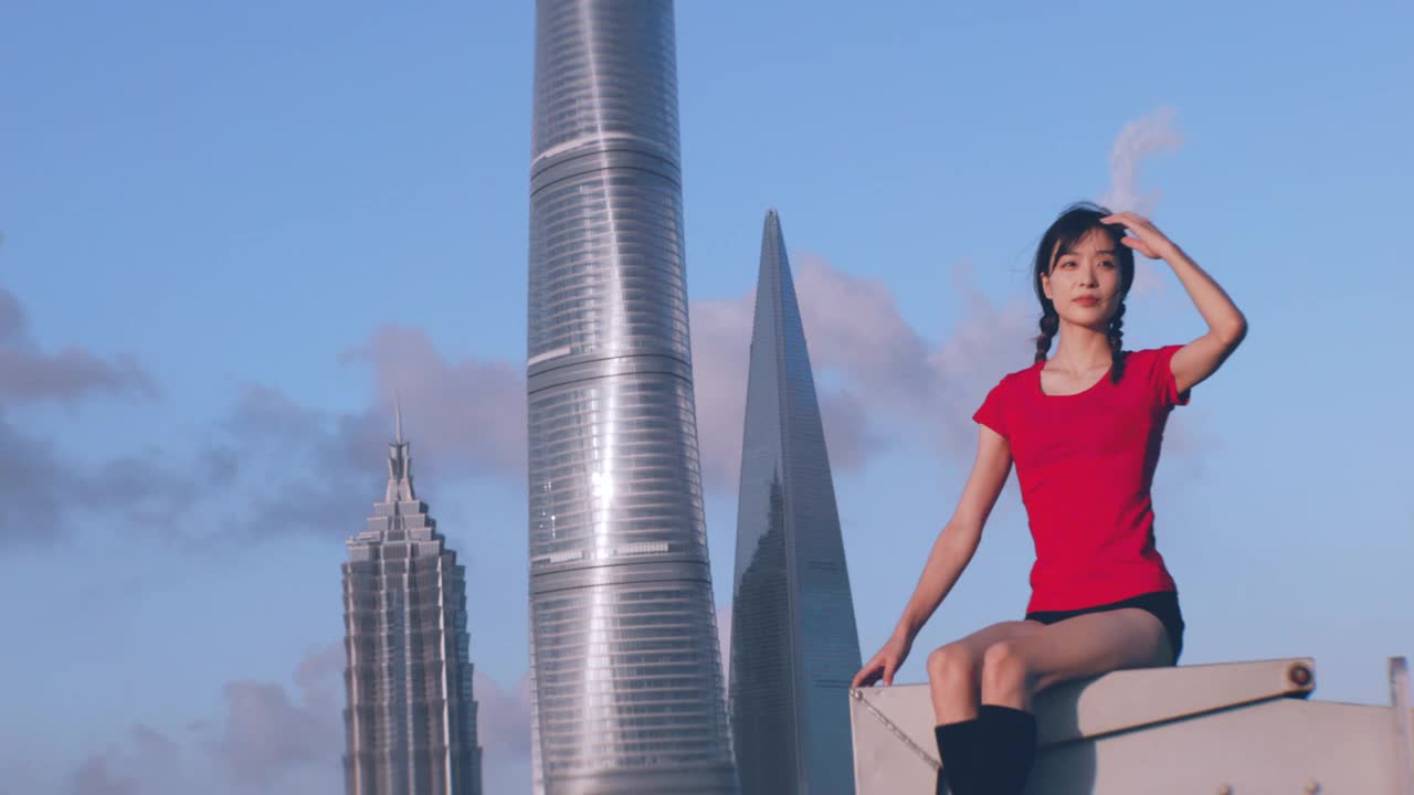 一个美丽的亚洲芭蕾舞女坐在屋顶上，向前看视频素材